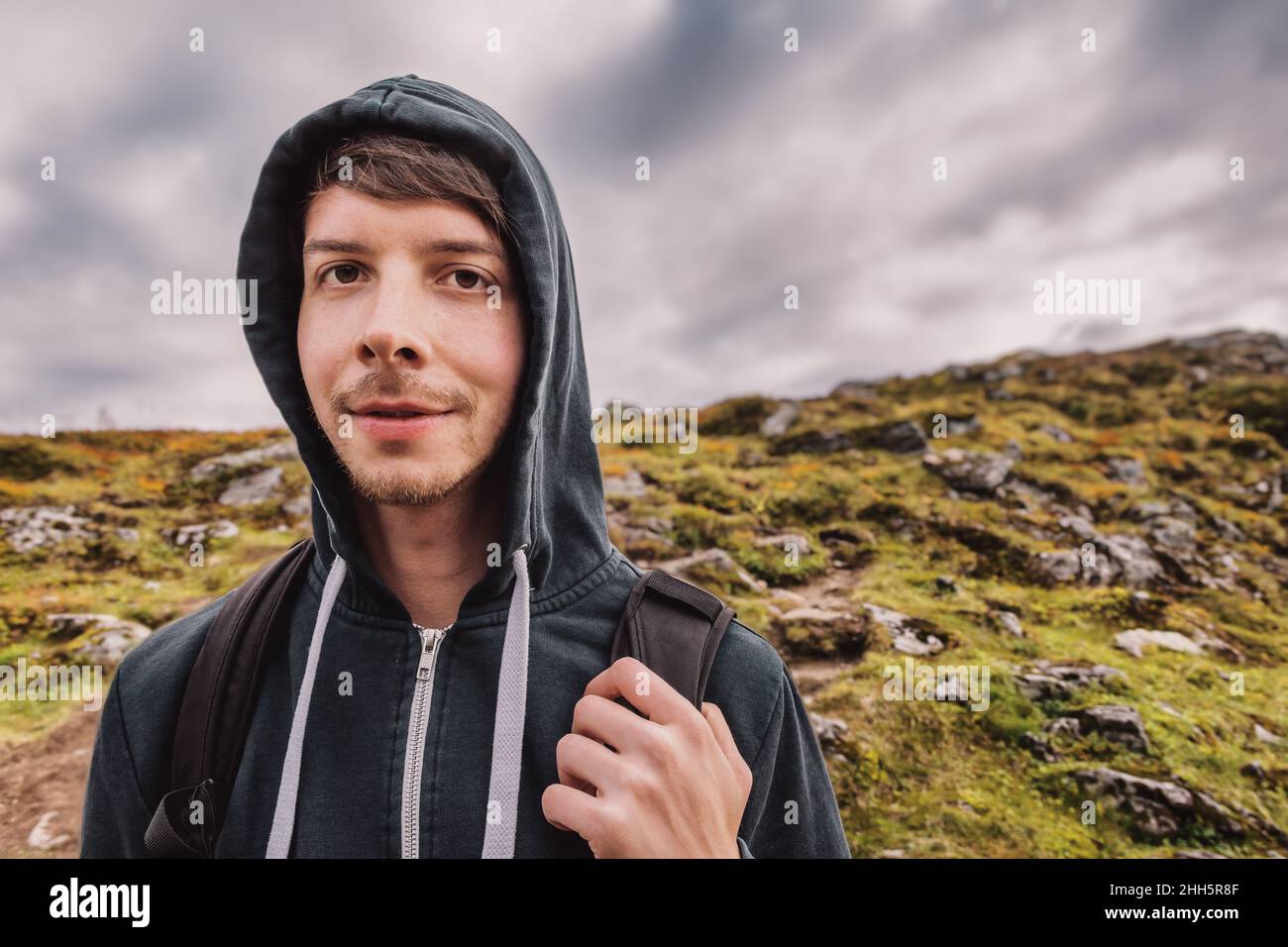 Jeune homme adulte avec des cheveux bruns et la barbe randonnée au sommet d'une montagne, portant un sac à dos, regardant l'appareil photo, automne, volda,norvège Banque D'Images