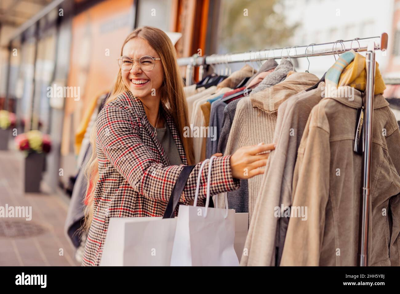 Un jeune client heureux qui choisit des manteaux d'hiver suspendus pour la vente à l'extérieur du magasin Banque D'Images