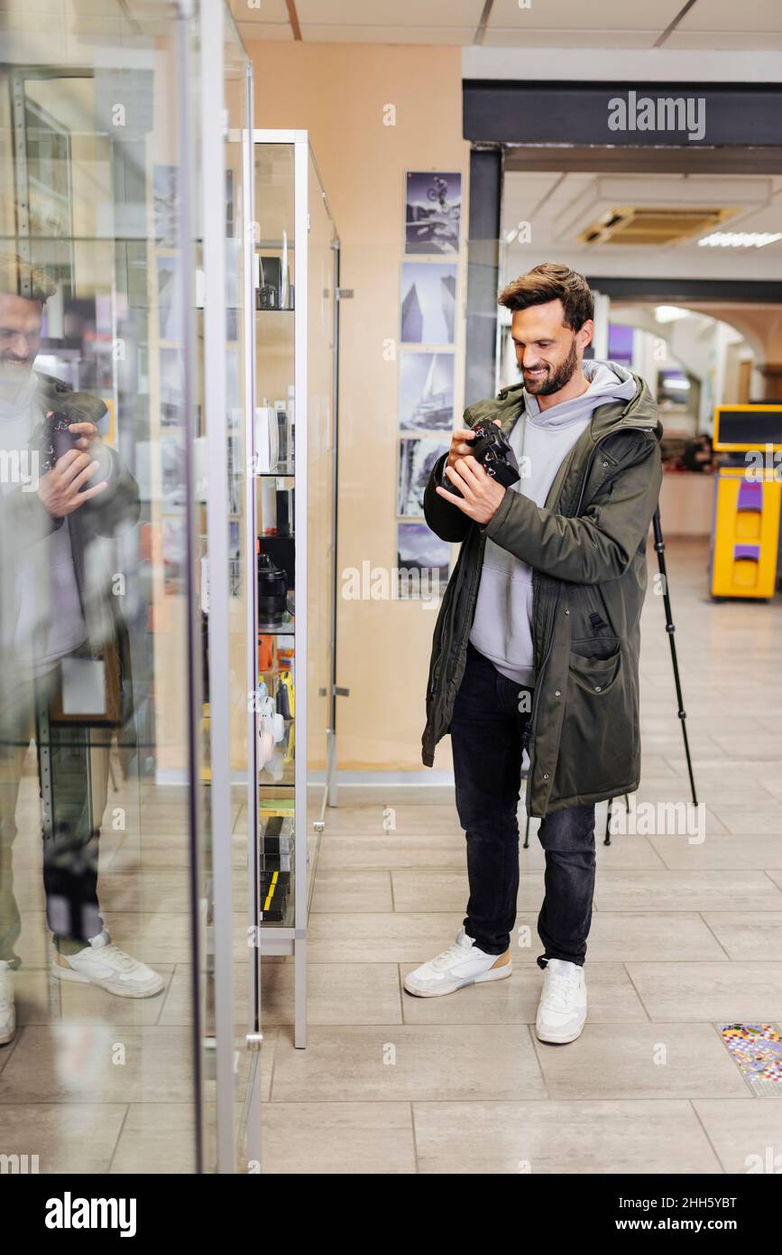 Homme souriant magasiner caméra dans le magasin Banque D'Images