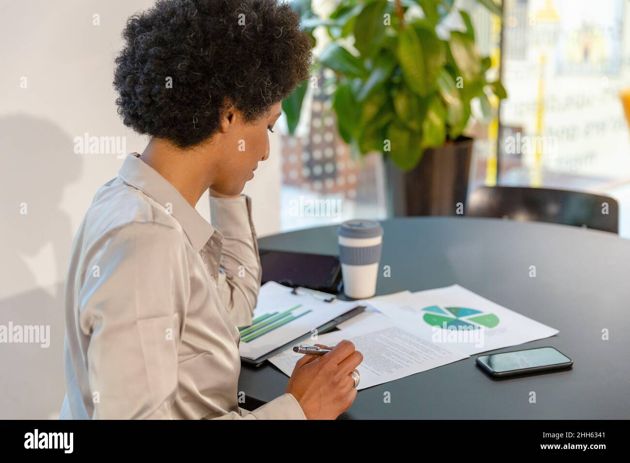 Une femme d'affaires remue-méninges sur le document à la table au bureau Banque D'Images
