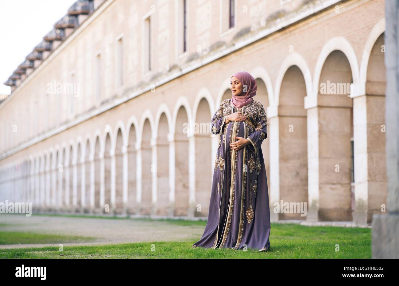 Femme enceinte avec les mains sur le ventre debout dans le parc Banque D'Images