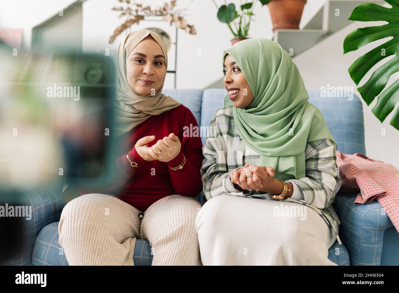 Des amis souriants aux mains classed assis sur le canapé dans le salon Banque D'Images