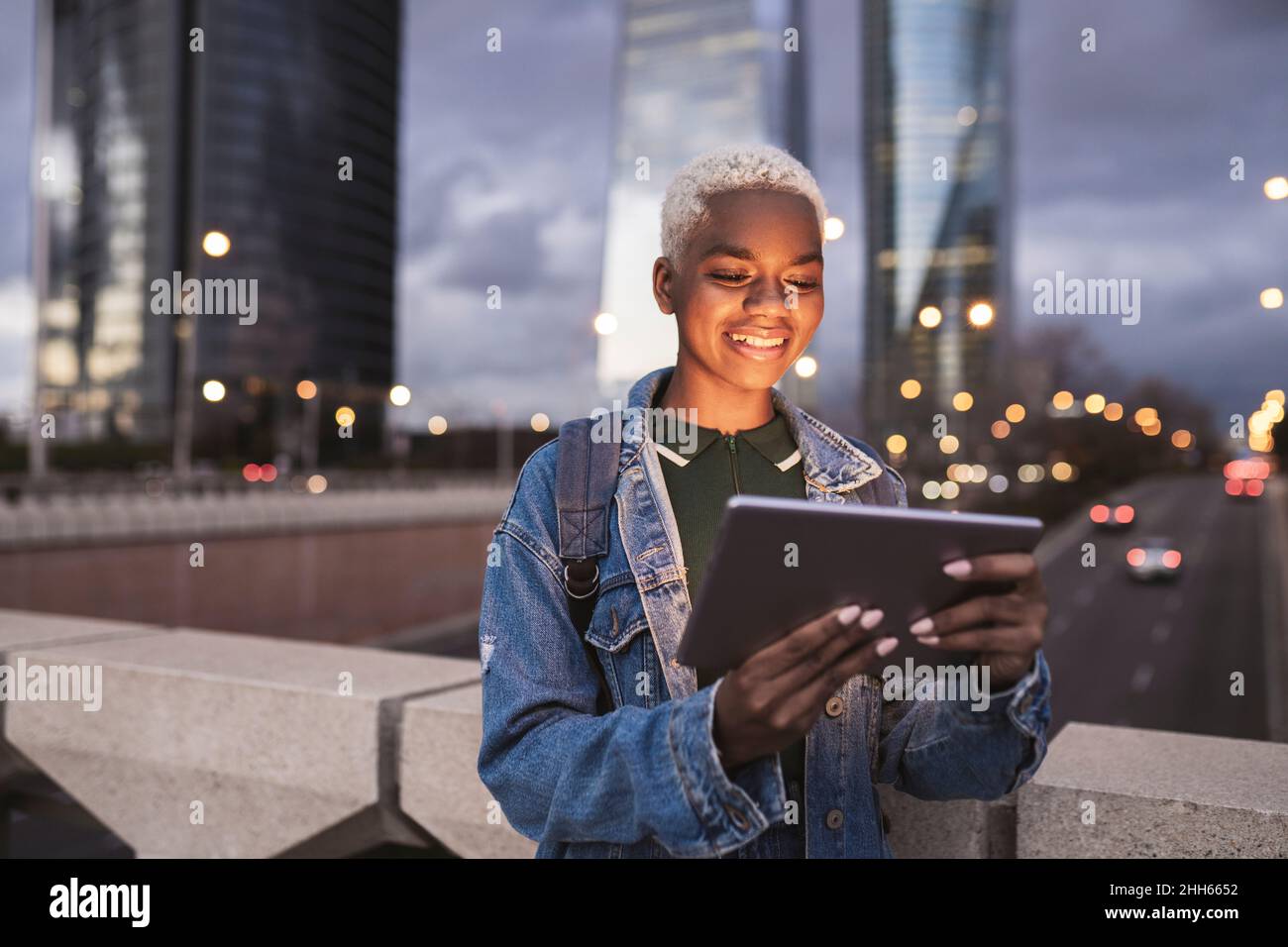 Femme souriante utilisant une tablette PC debout sur le pont en ville Banque D'Images