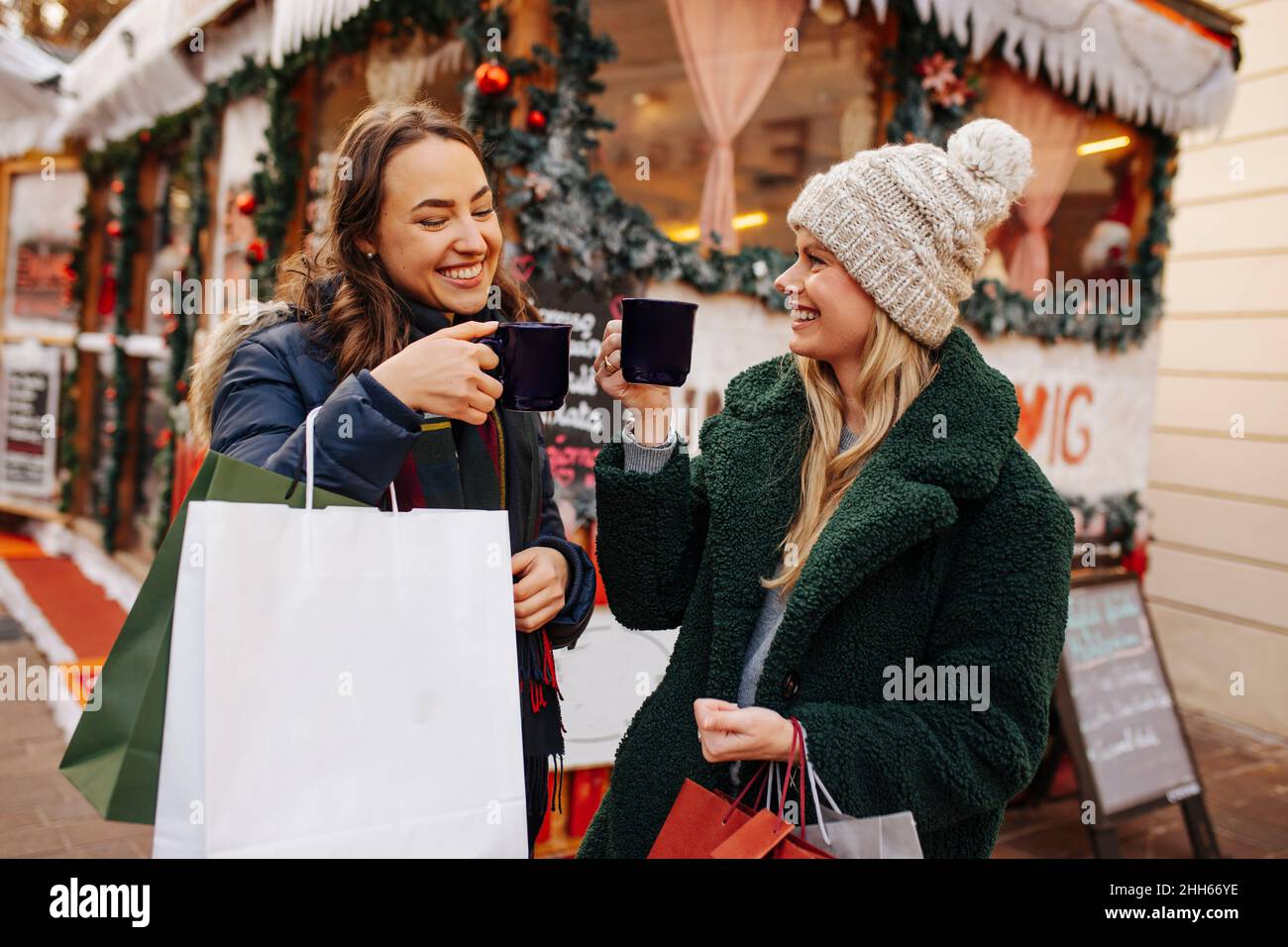 Des femmes souriantes toastent un mug à vin chaud au marché de Noël Banque D'Images