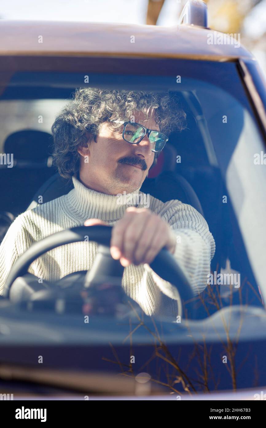 Homme attentif avec lunettes de vue conduisant une voiture vue à travers le pare-brise Banque D'Images