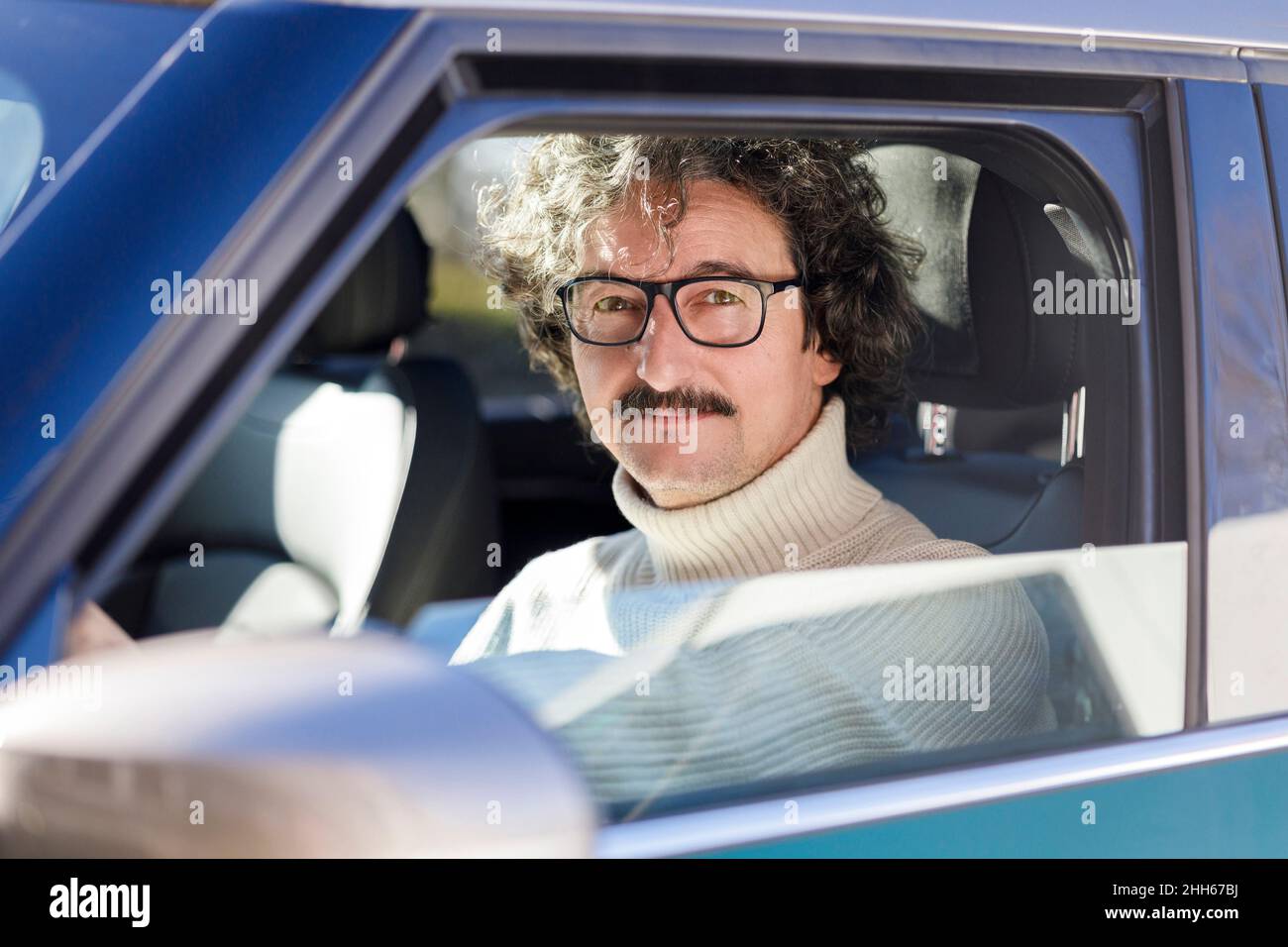 Homme avec des lunettes assis à l'intérieur de la voiture Banque D'Images