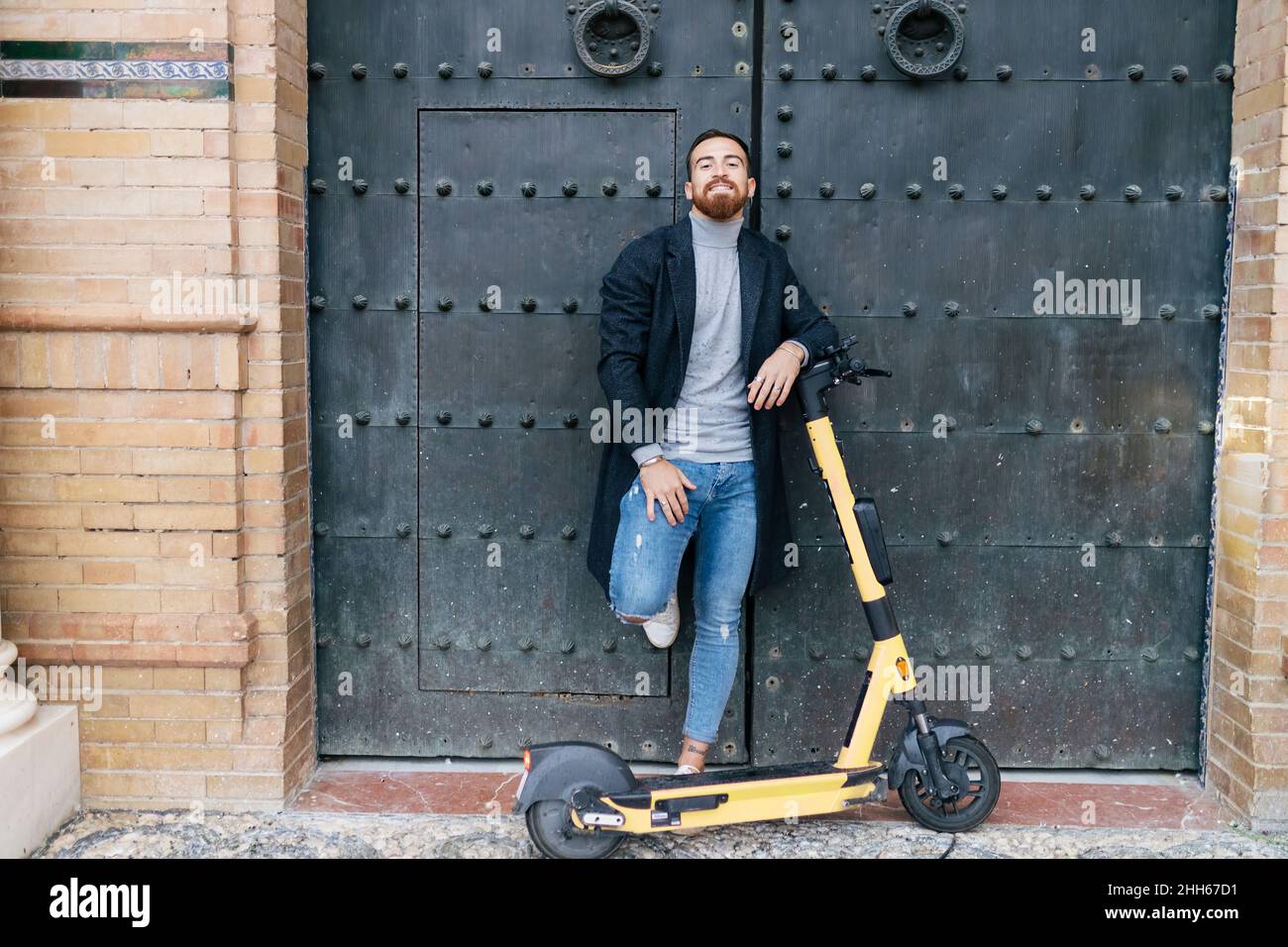 Jeune homme avec e-push scooter penché sur la porte fermée Banque D'Images