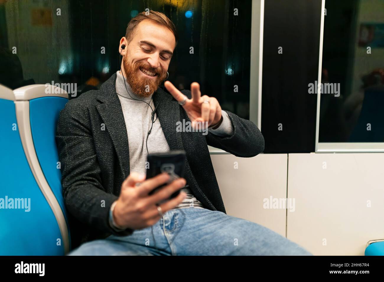 Homme prenant le selfie à travers le smartphone avec le signe de paix dans le tram Banque D'Images