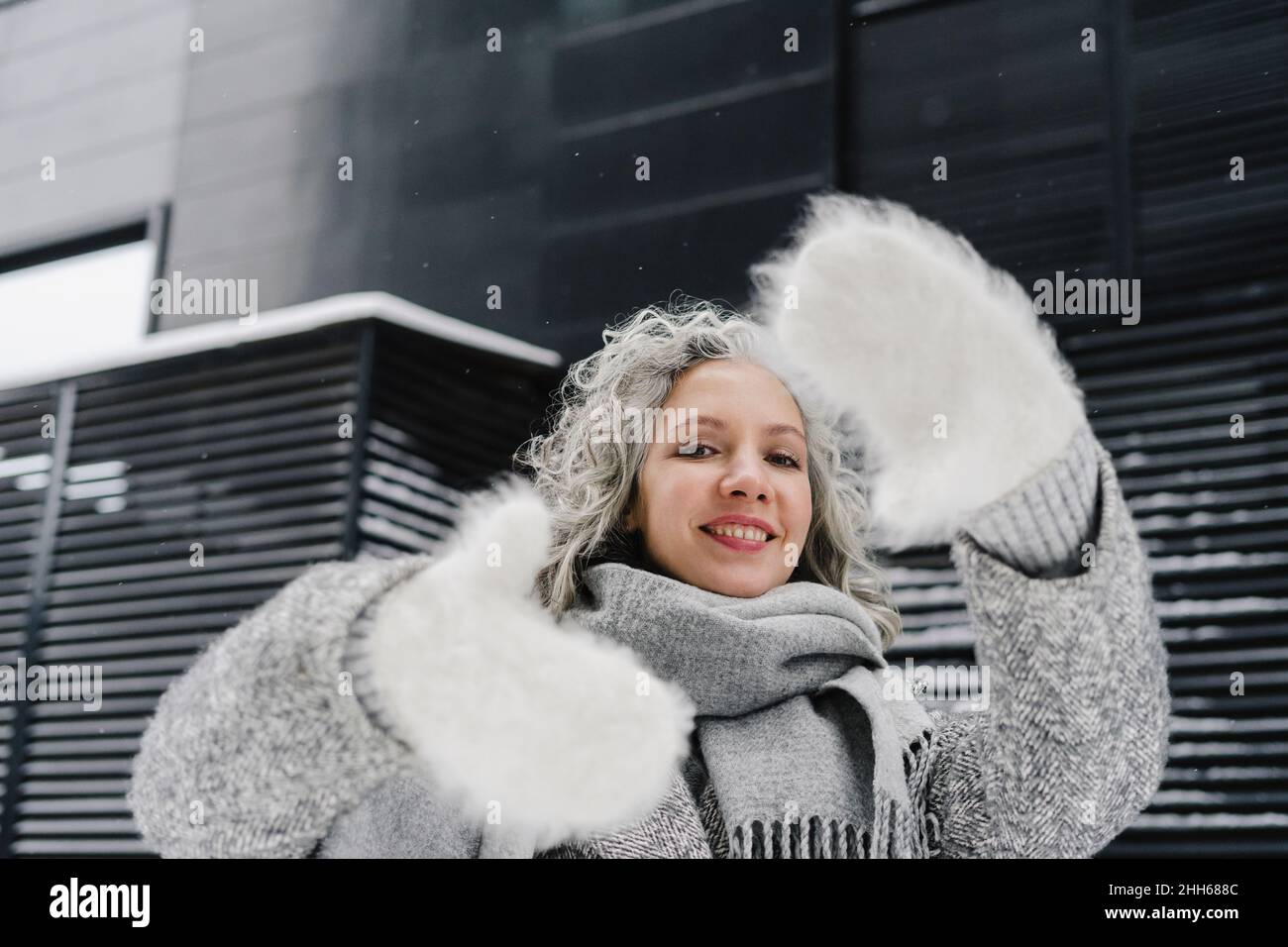 Femme souriante faisant porter des gants de fourrure faisant le cadre du doigt Banque D'Images