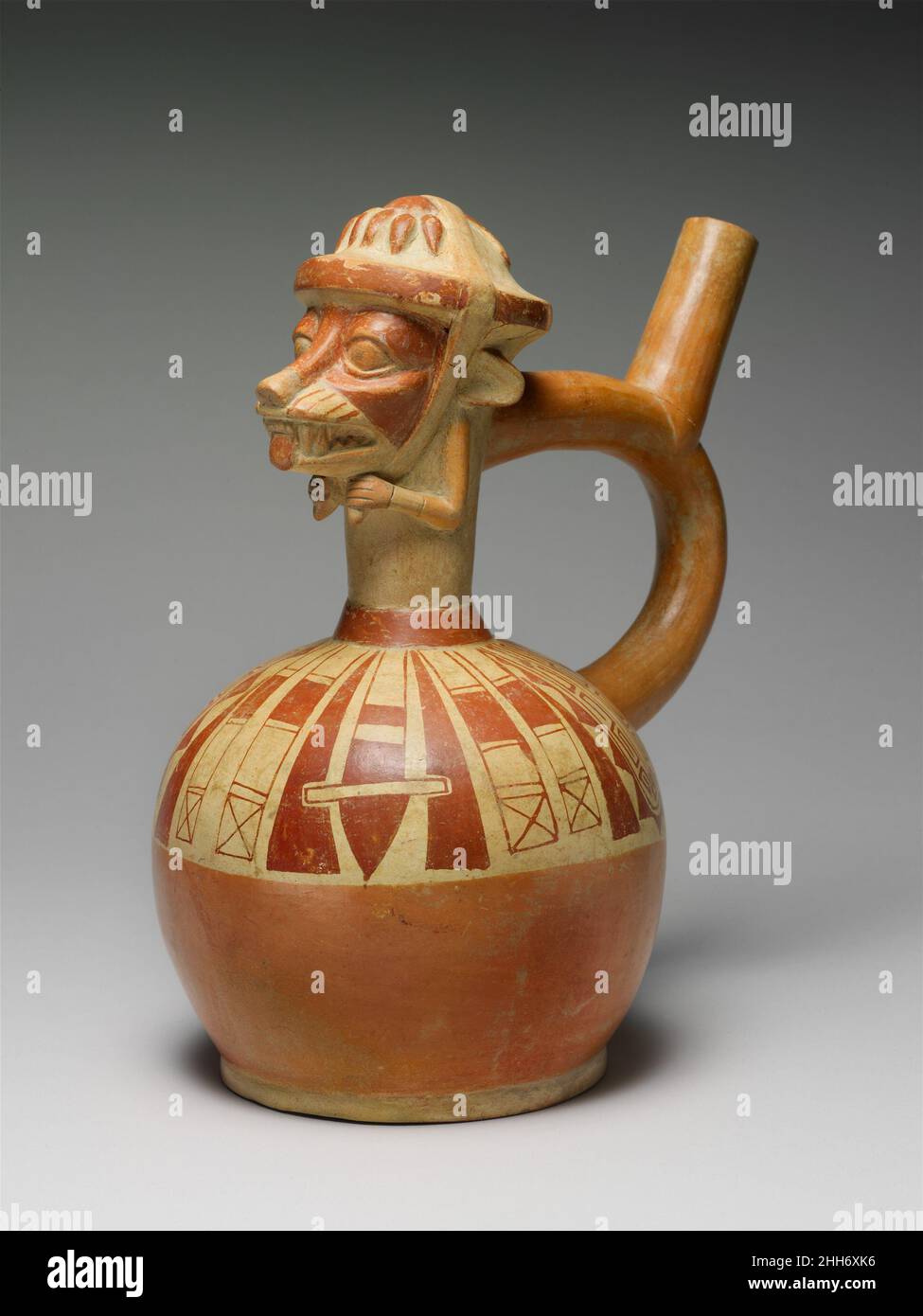 Fox Warrior Bottle 4th–6th Century Moche cette bouteille à bec d'étrier, conçue par des gens de la culture Moche sur la côte nord du Pérou, représente un renard anthropomorphique avec des attributs humains représentés en trois dimensions.Le dessus tridimensionnel de la bouteille peut être interprété soit comme un club de guerre zoomorphisé, soit comme un guerrier de renard nouant un headaddress en forme de mace sous son menton.Un spray de fruits ou de tubercules, peut-être des poivrons, est modelé sur le sommet du club.Les clubs, les lances et les cordes de casque peintes en rouge glissent du cou du navire à la circonférence de la chambre.Dans deux et thr Banque D'Images