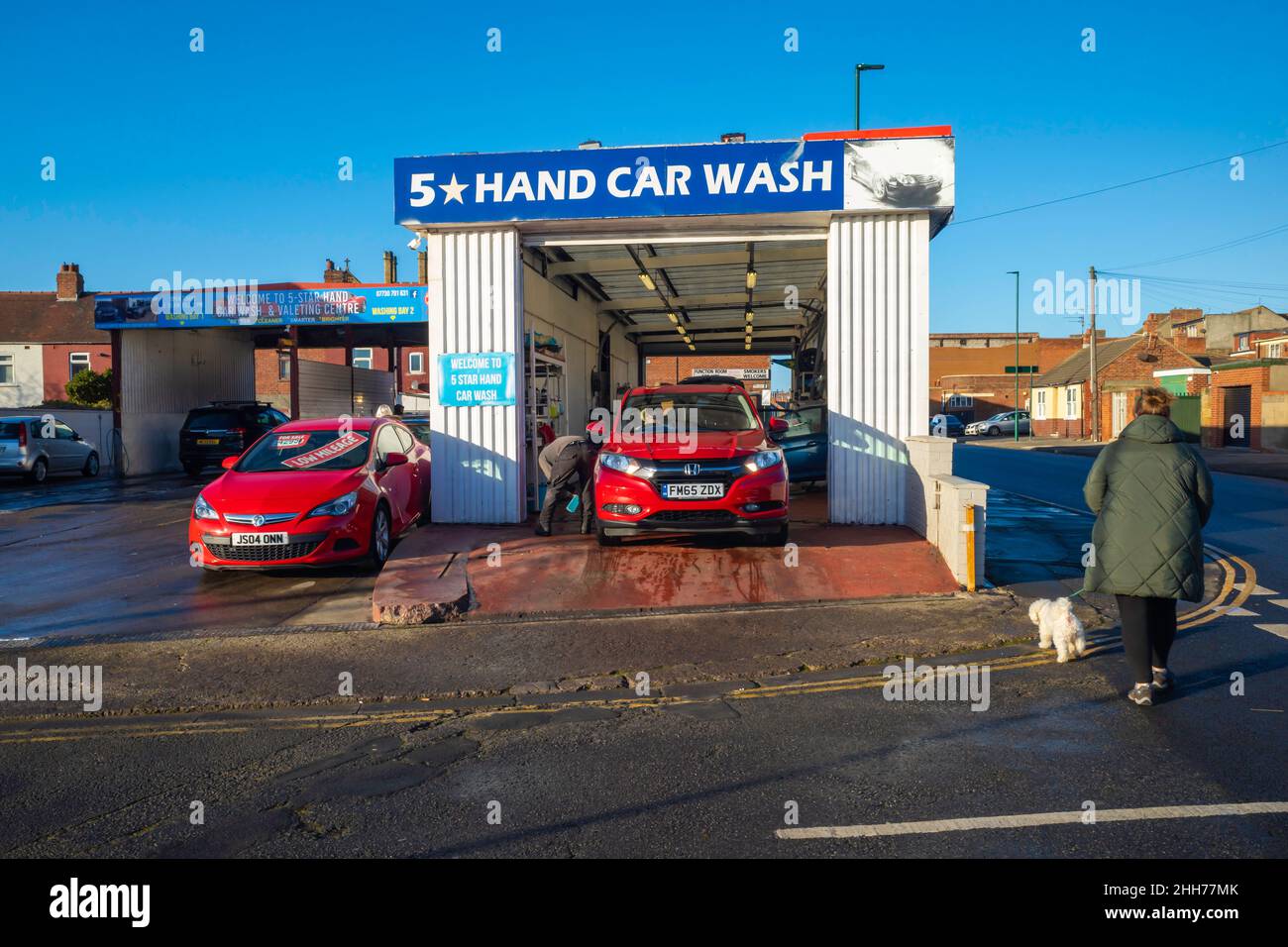 Les gens qui nettoient des voitures sur une voiture cinq* lavent le Redcar Cleveland North Yorkshire pendant qu'une femme passe avec un chien Banque D'Images