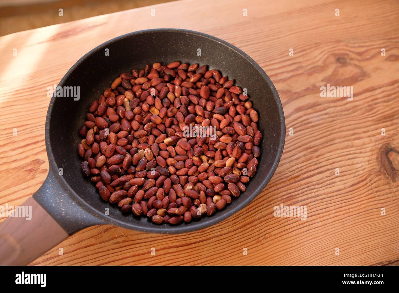 Les arachides frites dans une poêle à frire sur une table en bois. Banque D'Images