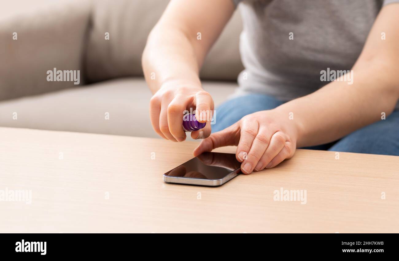 Photo rognée d'une femme méconnue qui nettoie son appareil ou l'écran de son téléphone à la maison Banque D'Images