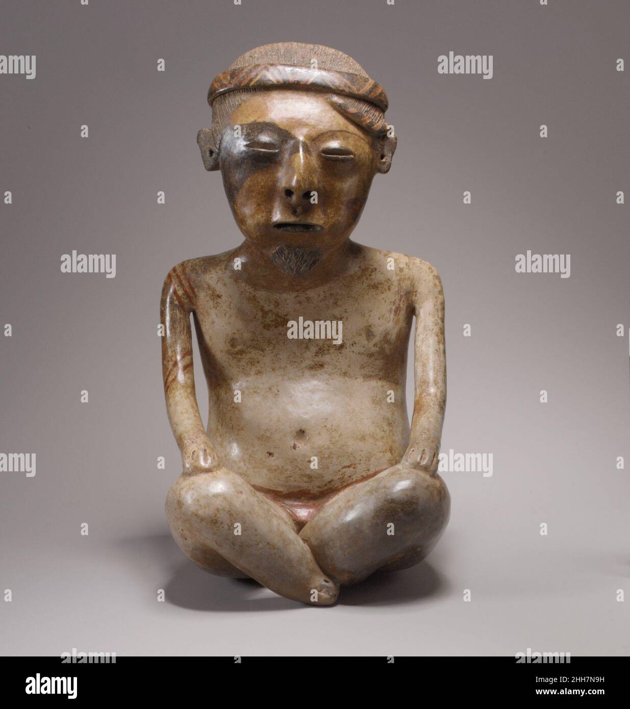 Figure masculine assise 2nd–4th siècle des sculptures appariées de Nayarit (Chinesco) représentant des figures mâles et femelles se produisent fréquemment parmi les biens funéraires des tombes de puits dans l'ouest du Mexique.Construits sous les plates-formes de la maison, ces tombes servaient de mausolées familiales et étaient périodiquement ouverts entre les personnes récemment décédées.Ces deux figures en céramique sont des représentations fines du style Nayarit connu sous le nom de Chinesco, remarquable pour les surfaces lisses brunies et l'ornement peint.Ceux-ci contrastent avec les lourds costumes tridimensionnels et les bijoux portés par des figures dans un autre style local, le style Ixtlán del Río Banque D'Images