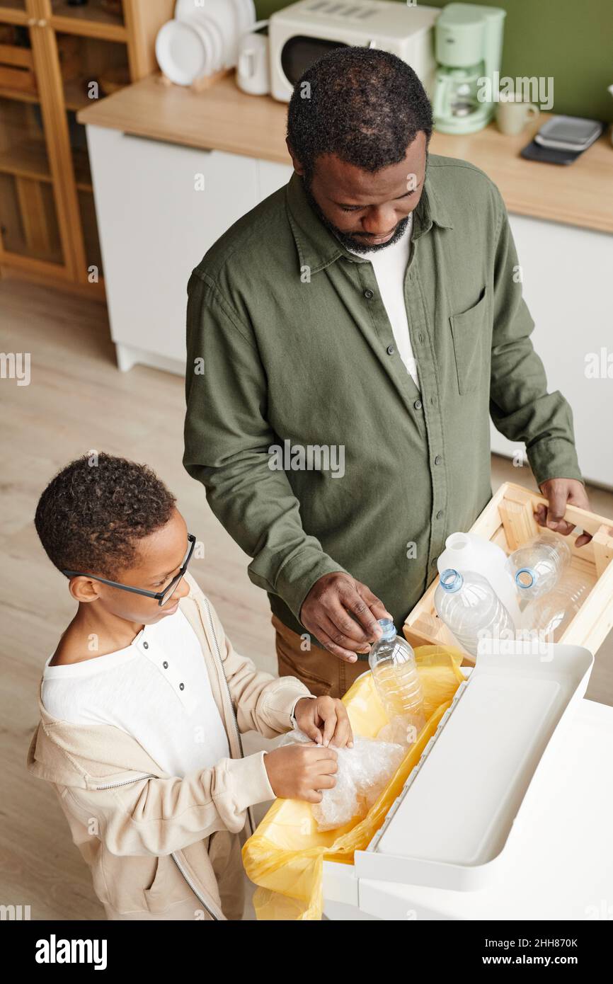 Portrait vertical en grand angle du père et du fils afro-américains qui triait les déchets ménagers chez eux Banque D'Images