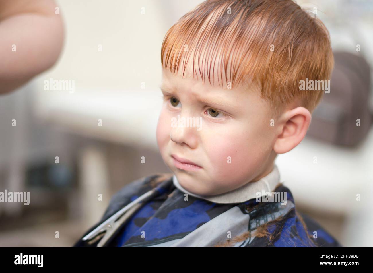 Petit garçon aux cheveux rouges au salon de coiffure.L'enfant n'aime pas  avoir une coupe de cheveux.Triste garçon de 4 ans Photo Stock - Alamy