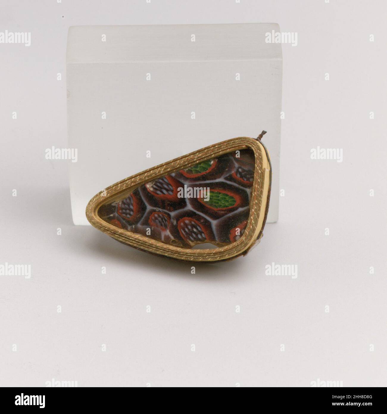 Fragment de bol en mosaïque de verre fin du 1st siècle C.-B.–début du 1st siècle A.D. Roman fragment de corps à parois minces.violet translucide avec stries incolores, bleu turquoise apparaissant vert, blanc opaque, rouge et jaune.côté incurvé de Convex.motif en mosaïque formé de sections polygonales de deux cannes soulignées en blanc :L'un sur un sol violet avec un cercle rouge enfermant un motif de points blancs sur un sol violet, et l'autre sur un sol violet avec un cercle rouge enfermant une dispersion de tiges bleu turquoise entourée de jaune.extérieur poli; piqûres et légère altération des bulles de surface à l'extérieur;terne Banque D'Images