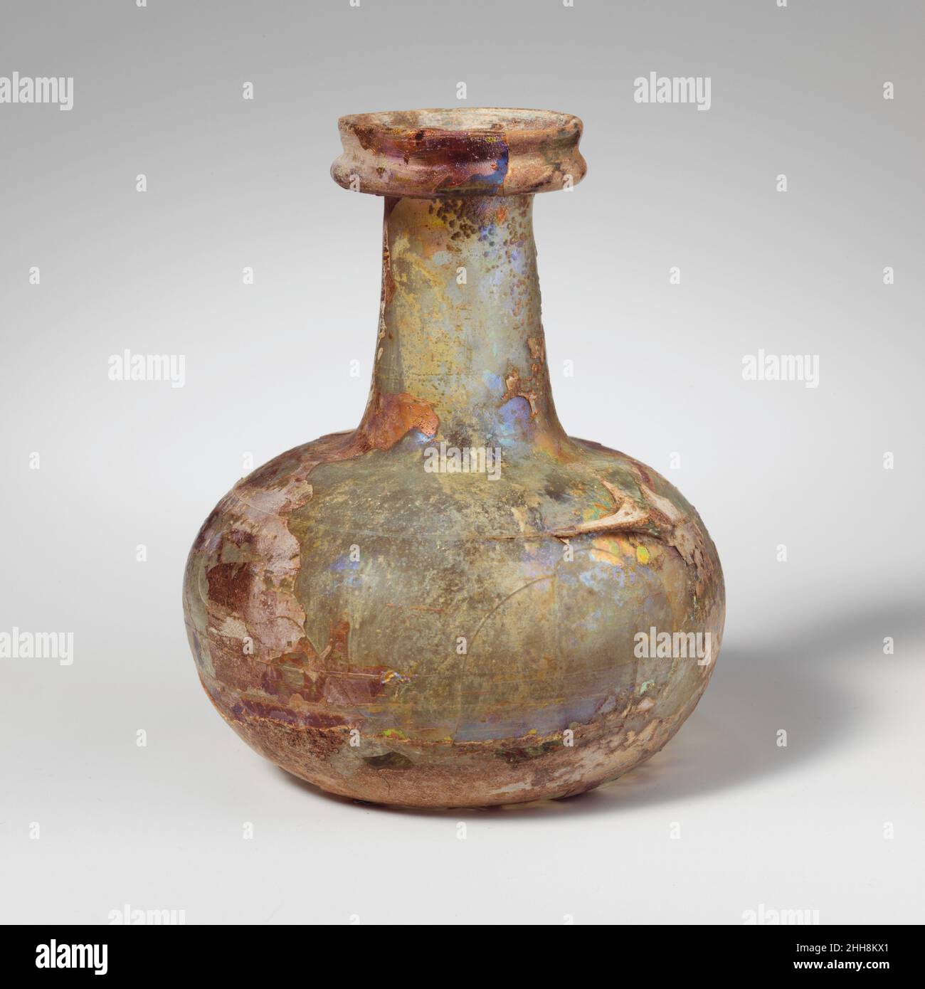 Flacon en verre 2nd–3rd Century A.D. Roman translucide bleu pâle vert, avec même couleur de couleur de trace.rebord en col, plié, vers le bas, rond, extérieur,et vers le haut, avec un niveau de bouche, puis vers le haut et légèrement vers l'extérieur, avec une lèvre verticale arrondie; un col cylindrique, en expansion vers le bas, légèrement aplati d'un côté sous le bord; une épaule arrondie; un squat, un corps globulaire;Fond enfoncé avec repère de pontil central.le chemin en spirale est appliqué sur le bord extérieur de l'épaule dans le grand coussin et est étiré vers le bas du corps.intact, sauf pour les fissures et les deux trous dans le corps; une grande partie de la décoration de sentier est manquante; des bulles piquées; piqûres profondes et Banque D'Images