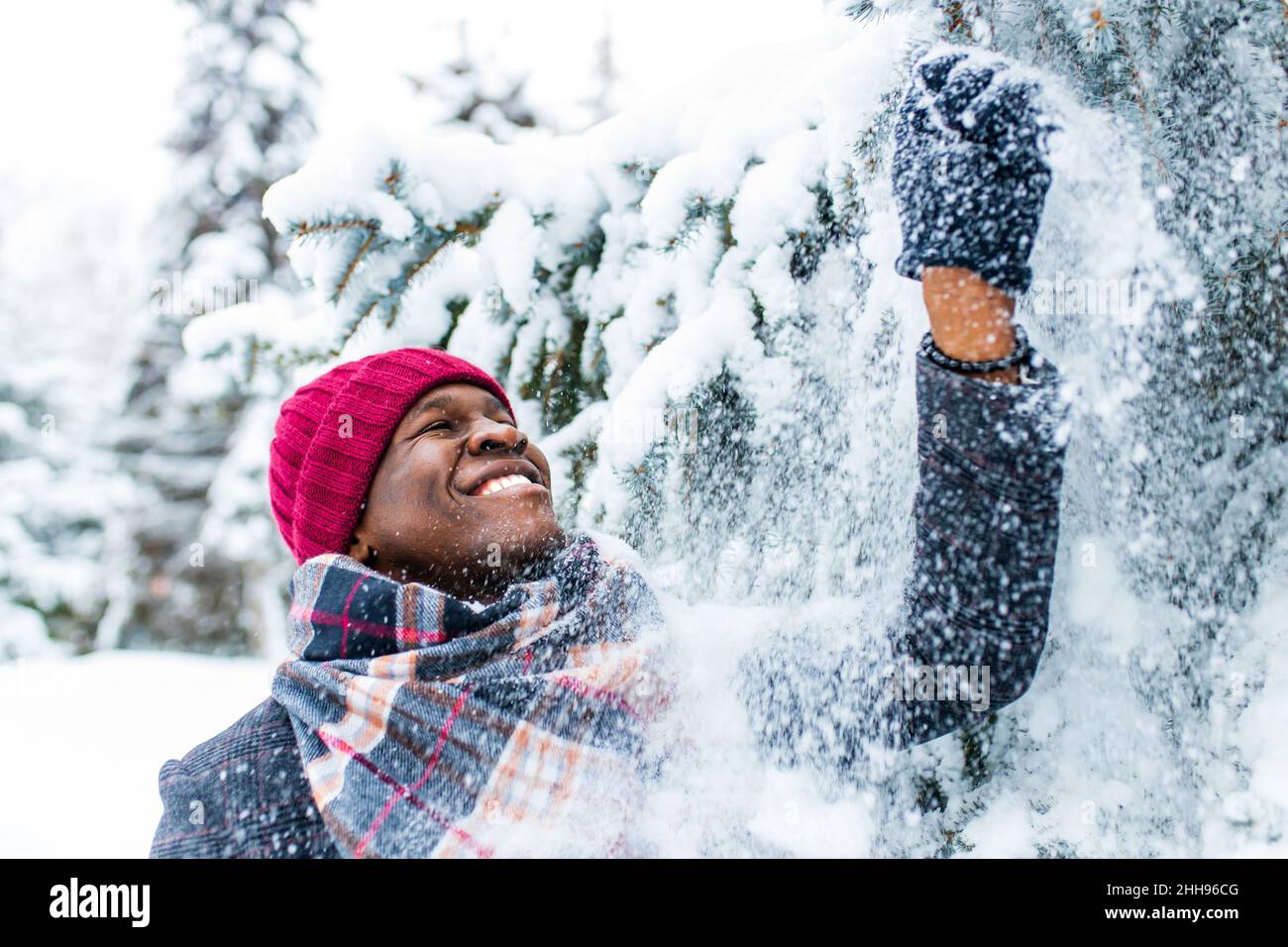 homme afro-américain dans une forêt enneigée d'hiver avec des flocons de neige tombant de forêt d'épinette et de sapin Banque D'Images