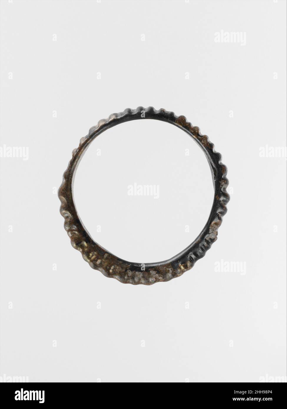 Bracelet en verre 4th Century A.D. Roman bleu foncé translucide, paraissant opaque noir.bande légèrement ovale, large et étroite dans la section d'un côté, mince et profond de l'autre;Aucun joint visible mais marques d'outillage sur la surface intérieure.surface extérieure décorée de trente-neuf nervures verticales ou globulaire.intact, sauf pour la bande de copeaux et de fissures; morcellement et taches d'intempéries irisées.Bracelet bleu.Bracelet en verre 239936 Banque D'Images