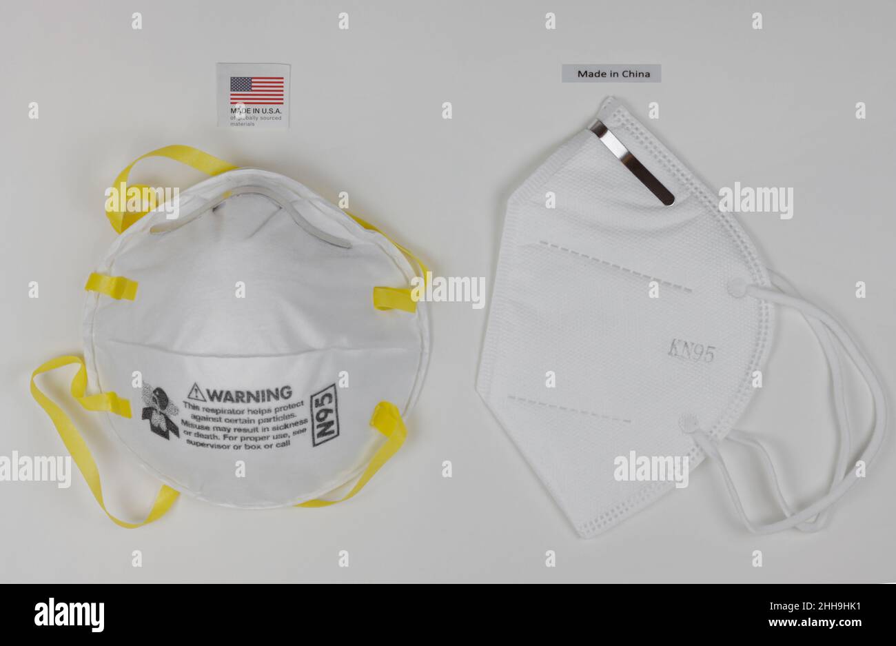 Masque respiratoire N95 fabriqué aux Etats-Unis à côté d'un masque facial KN95 fabriqué en Chine, avec des étiquettes ci-dessus, sur fond blanc Banque D'Images