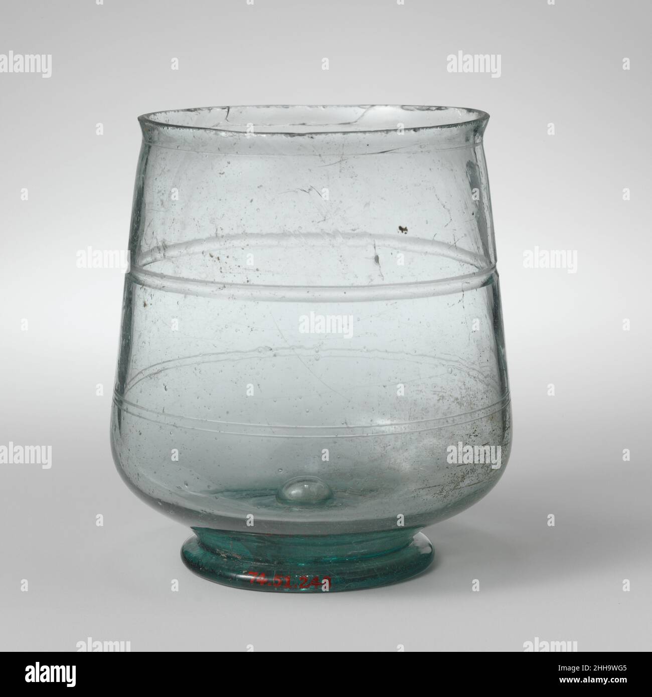 Bécher en verre probablement 3rd siècle A.D. Roman, Cypriote bleu translucide vert.Plain, rebord renflé, avec un petit collet en dessous; côtés droits au corps, en expansion vers le bas, puis en courbure vers une base solide et basse;Fond plat, avec un coup creux central, formant un bouton de projection à l'intérieur.Décoration de lignes horizontales bien exécutées, comprenant une seule ligne fine sous le col, une gorge large et profonde sur le haut du corps, et une bande de deux lignes fines sur le bas du corps.intact, mais de nombreuses fissures internes, en particulier dans la base;quelques petites bulles et des bulles plus grandes, et quelques inclusions vitreux; très peu nous Banque D'Images