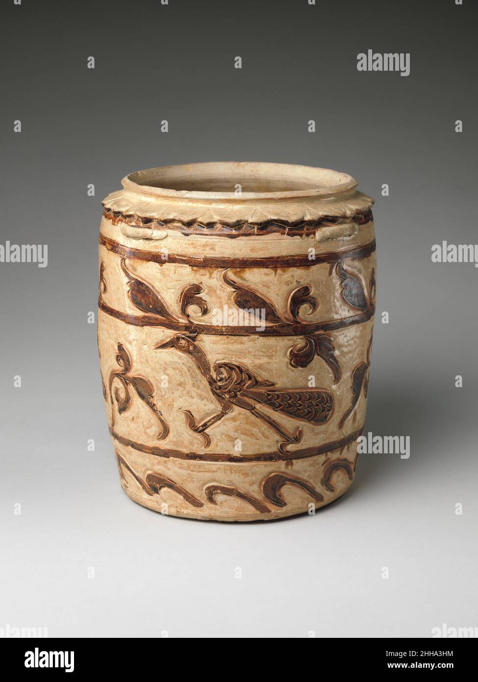 Pot de rangement ca.13th Century Vietnam un pot de stockage émaillé d'ivoire avec oiseau de forêt et motif de feuillage incisé dans l'argile et mis en évidence dans un sous-vernis de lavage de fer.Il est doté d'un col en pétales de lotus sculpté en saillie sous le rebord et de quatre poignées de patte résiduelles sur l'épaule.Les bocaux de ce type ont été conçus pour avoir une couverture, mais ceux-ci survivent rarement.Une de ces couvertures est conservée dans les Musees Royaux, Bruxelles, et est inscrite en lave-fer sur la surface intérieure 'conteneur à vin'.Cela reste l'indicateur le plus définitif de la fonction de ces bocaux énigmatiques.Les conceptions choisies sont Ty Banque D'Images