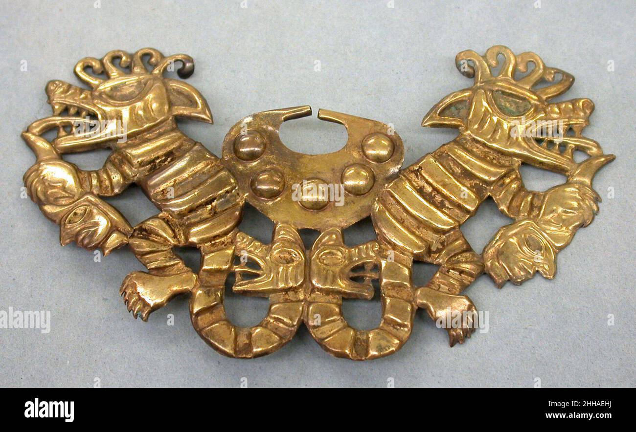 Nez décoratif 6th–7th Century Moche (Loma Negra) cet ornement de nez doré à ouverture représente deux créatures surnaturelles, toutes deux avec des caractéristiques canines et félines, montrées dos à dos, chacune tenant une tête de trophée humaine.Les queues des créatures se terminent par des têtes qui s'arrachant, soulignant encore davantage le sentiment d'agression signalé par les oreilles de la créature, qui sont de retour.Des incrustations de pierre ou de coquille décoraient autrefois le corps des animaux, y compris leurs yeux, leurs oreilles, leurs troncs et leurs jambes.Lorsqu’il est porté, cet ornement du nez aurait couvert une grande partie de la bouche du porteur : peut-être l’imagerie puissante a-t-elle été pensée pour imprégner celui du porteur Banque D'Images