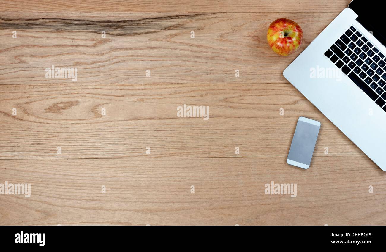 Bureau en chêne, table avec ordinateur portable, smartphone et pomme fruits pour le travail.Vue de dessus avec espace de copie au format de mise à plat. Banque D'Images
