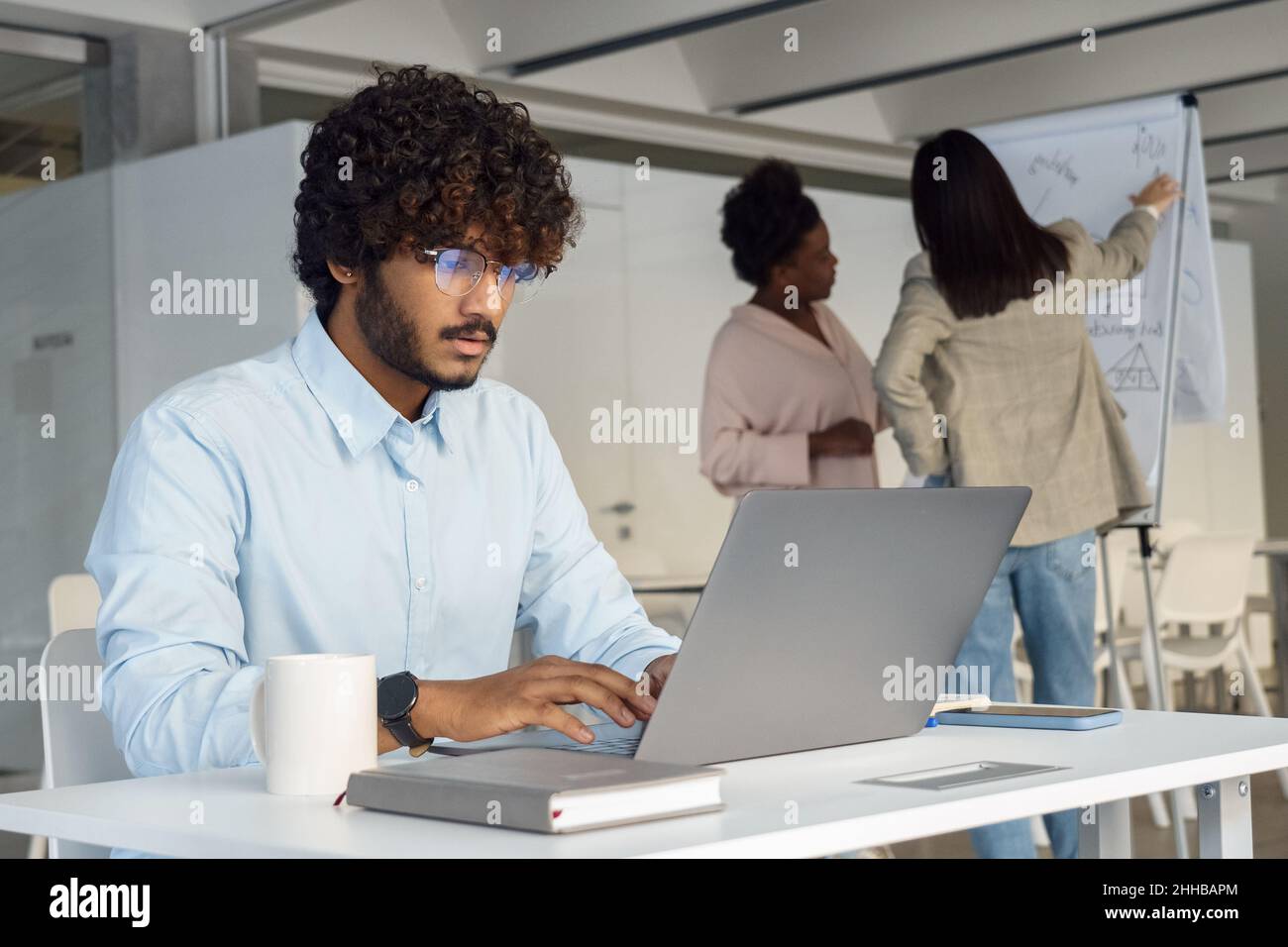 Un Indien sérieux travaillant sur un ordinateur portable au bureau de l'équipe d'ouverture de l'espace de démarrage Banque D'Images