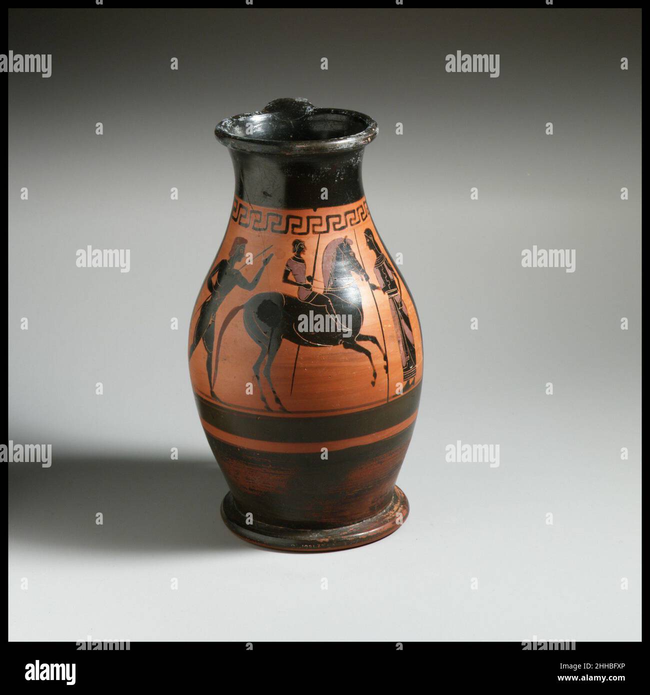 Terre cuite oinochoe: olpe (verseuse) ca.540 C.-B. grec, Atique Jeune cavalier entre les jeunes et les femmes l'olpe est une carafe caractérisée par une bouche qui est continue plutôt qu'articulée avec un bec.Cet exemple représente un type précoce dans lequel la bouche est noire plutôt que décorée.Le sens de la scène est étonnant, dans la mesure où les trois figures tiennent des lances.Il se peut que les jeunes quittent ou retournent à la maison; la femme avec une lance est probablement un membre du ménage.Terre cuite oinochoe: olpe (carafe) 247232 Banque D'Images