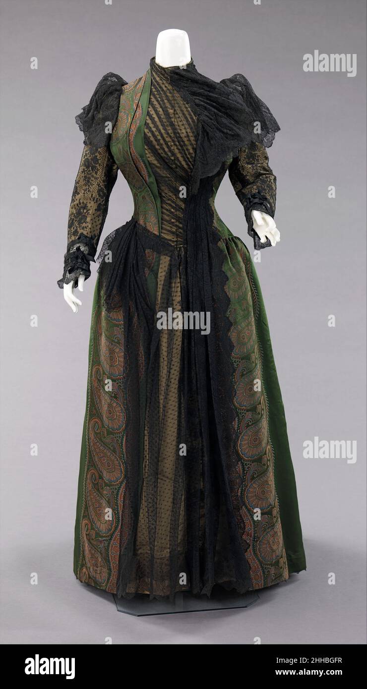 Robe 1889 Mme.Noll Gross la silhouette d'agitation, bien que principalement associée à la deuxième moitié du 19th siècle, a commencé dans les modes antérieurs comme une simple bosse à l'arrière de la robe, comme avec la fin 17th-début 18th siècle mantuas et fin 18th- début 19th siècle Empire robes.La silhouette pleine d'agitation avait sa première apparence victorienne à la fin de 1860s, qui a commencé comme la plénitude dans les jupes se déplaçant à l'arrière de la robe.Cette plénitude a été dressée en cravates pour la marche qui a créé une bouffée à la mode.Cette bouffée tendance s'est développée et a ensuite été construite avec des supports Banque D'Images