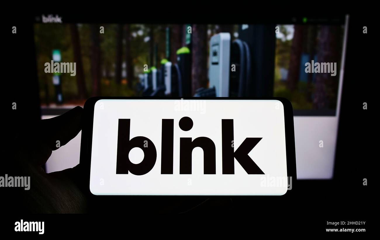 Personne tenant un smartphone portant le logo de la société américaine Blink Charging Co. Sur l'écran devant le site Web.Mise au point sur l'affichage du téléphone. Banque D'Images Personne tenant un smartphone portant le logo de la société américaine Blink Charging Co. Sur l'écran devant le site Web.Mise au point sur l'affichage du téléphone. Banque D'Images
