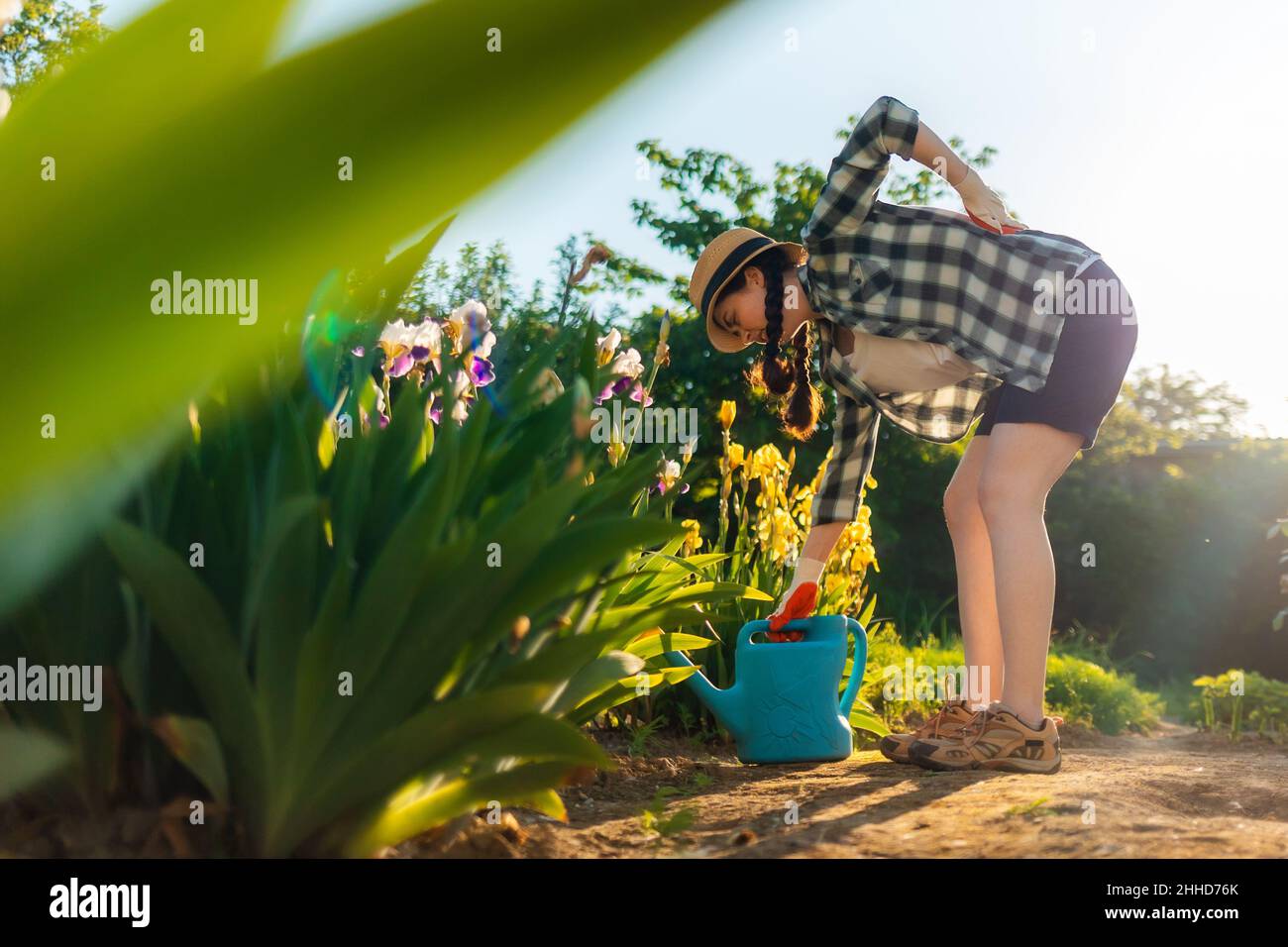 La femme caucasienne se tient pendue près d'un arbuste à iris en fleurs, la tenant dans la douleur.Vue de dessous.Le concept des problèmes de santé de dos. Banque D'Images