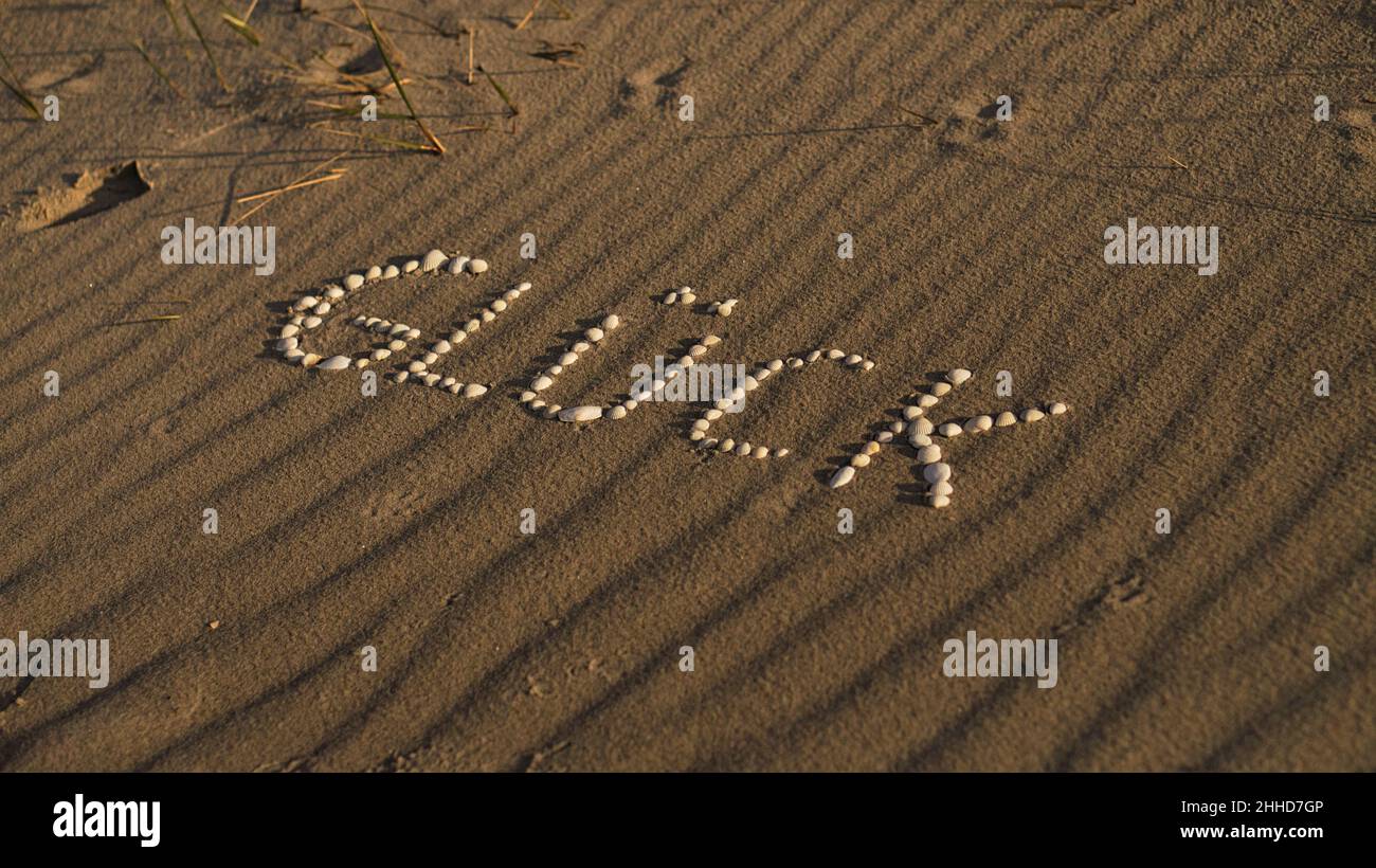 Avec des coquillages posés symbole bonheur sur la plage de la mer Baltique dans le sable.Souhaits pour les vacances et la vie. Banque D'Images