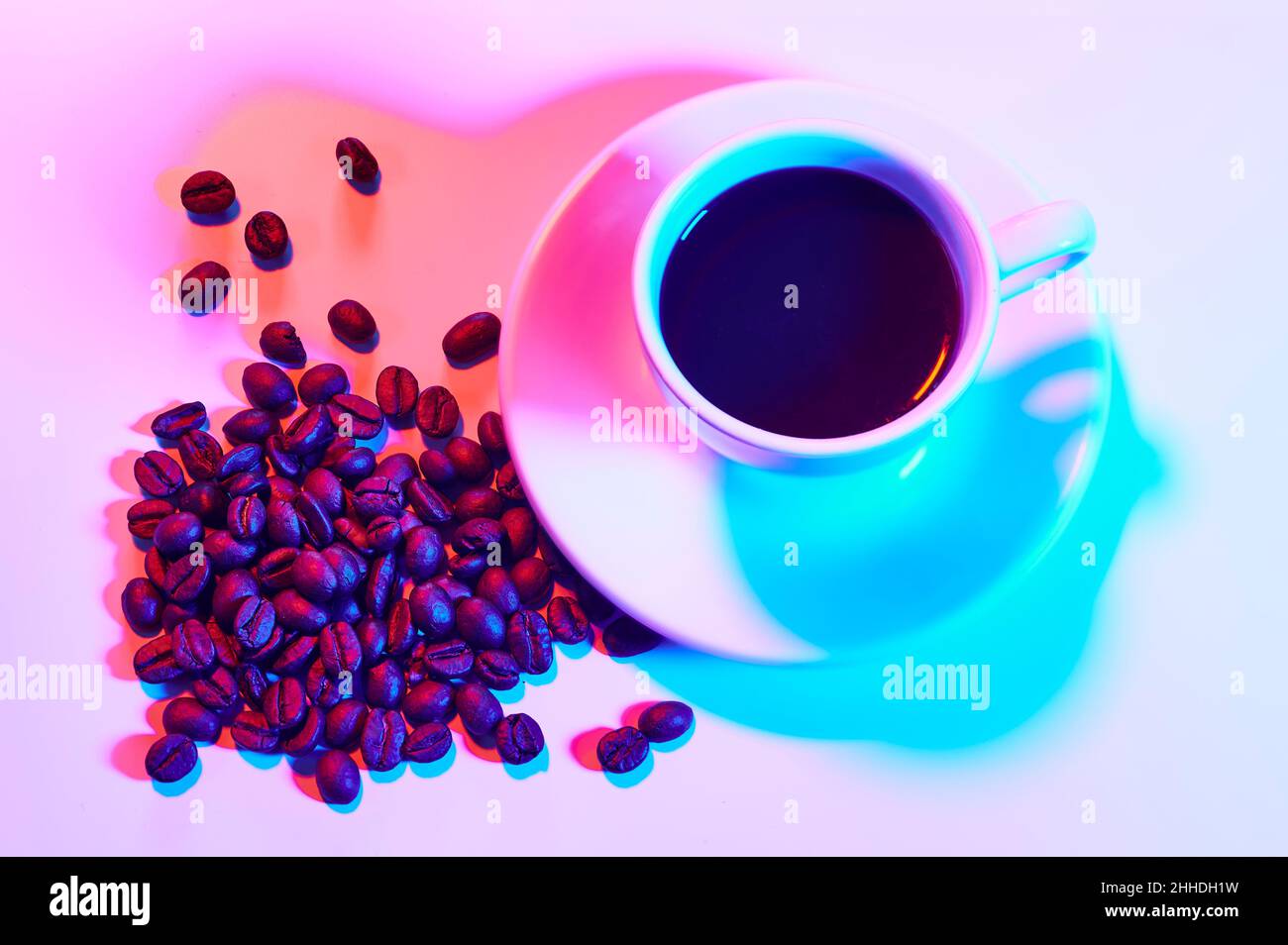 Tasse de café et grains de café torréfiés sous les lumières du coloriste Banque D'Images
