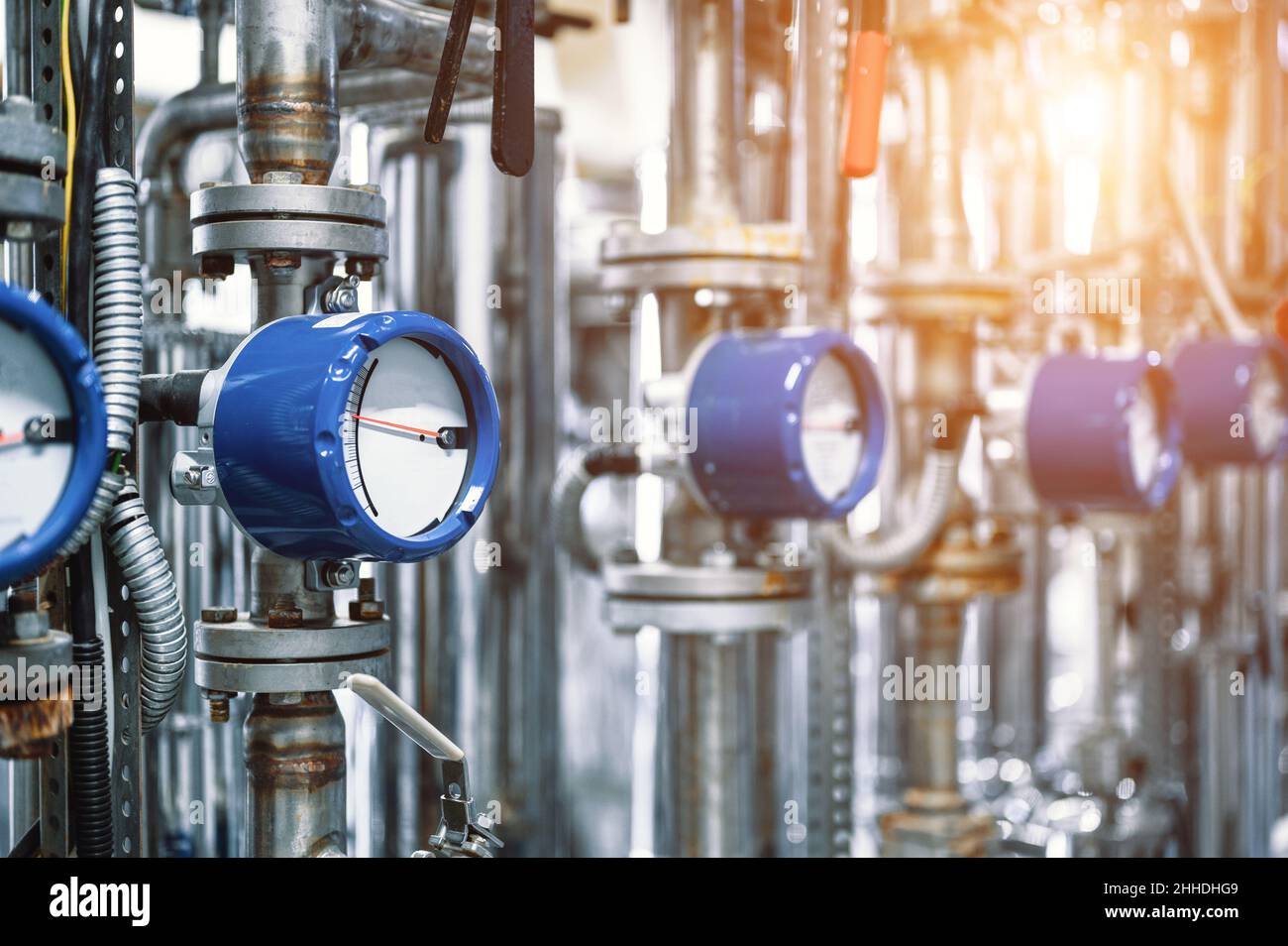 Débitmètres avec flèches dans des boîtiers bleus sur les tuyaux en atelier Banque D'Images