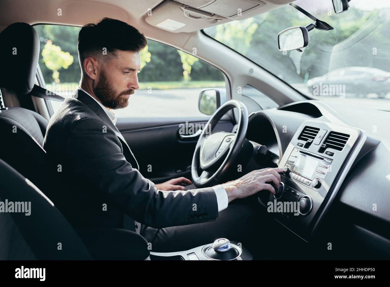 Homme d'affaires conduisant une voiture allume la musique dans le lecteur de voiture, un homme avant un voyage dans un costume d'affaires Banque D'Images