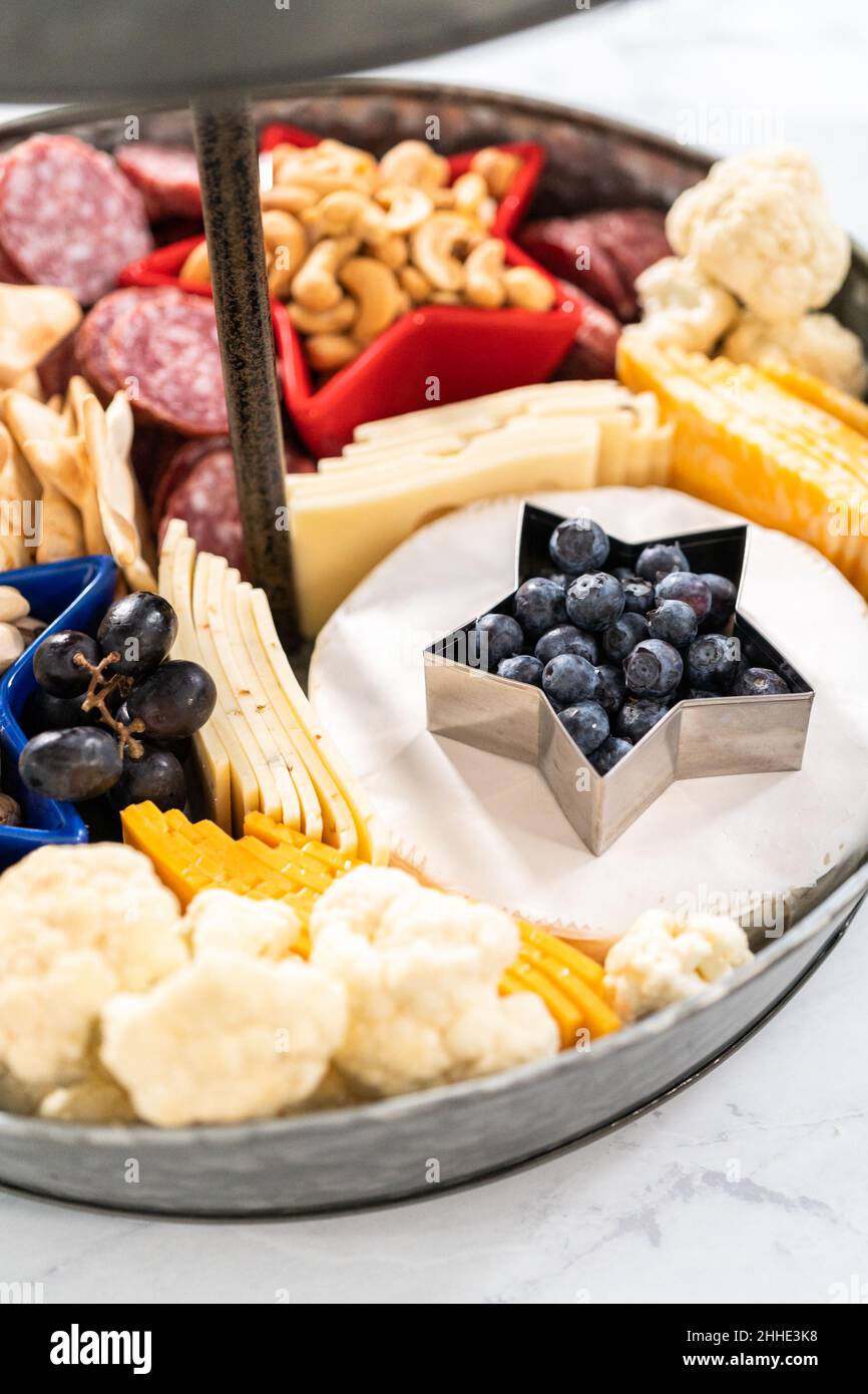 Le 4 juillet, un plateau de charcuterie est servi sur un support métallique à deux niveaux rempli de fromage, de craquelins, de salami et de fruits frais Banque D'Images