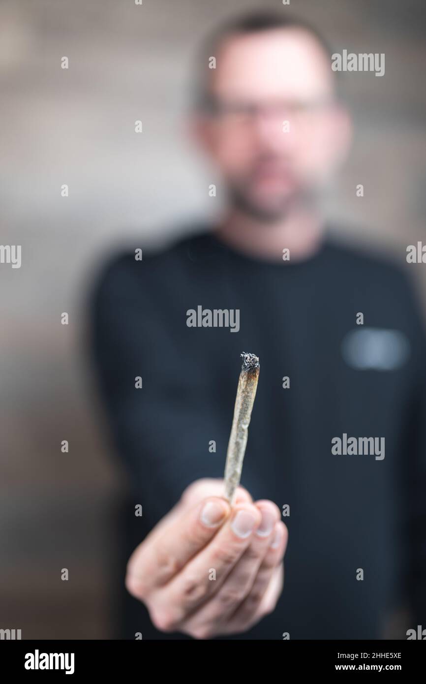Personne non reconnaissable ou floue offrant un joint. Éviter la pression des pairs par la prévention. Banque D'Images
