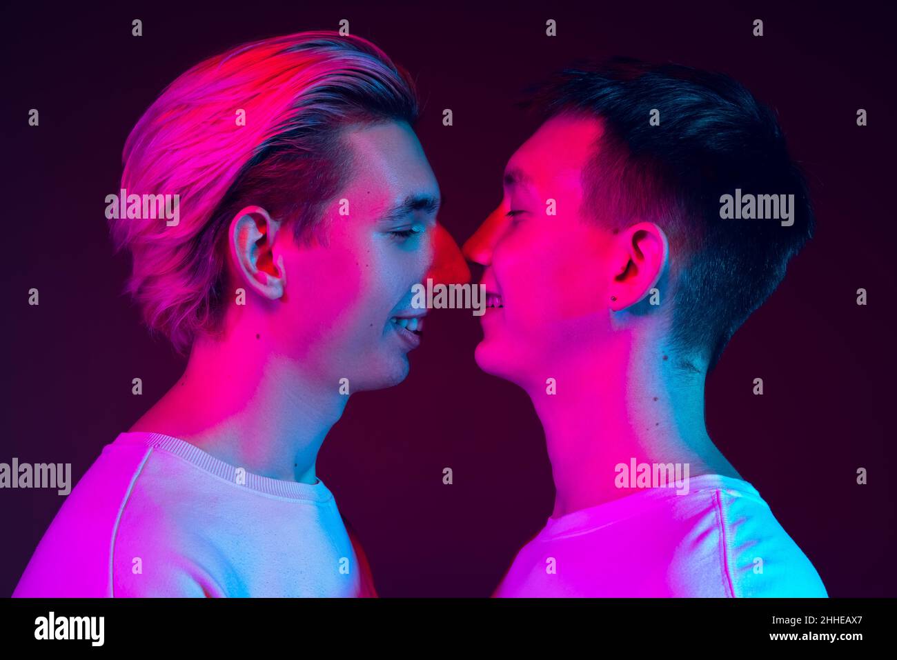 Gros plan deux jeunes hommes, couple embrassant isolé sur fond bleu à la lumière du néon.Concept des émotions, de l'amour, des relations, des droits de l'homme Banque D'Images