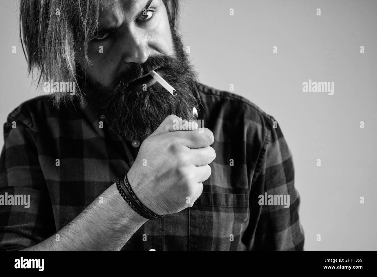 fume une cigarette. homme barbu. hipster mûr avec barbe utilisez un briquet. hipster caucasien brutal avec moustache fume cigarette. homme mauvaise habitude Banque D'Images