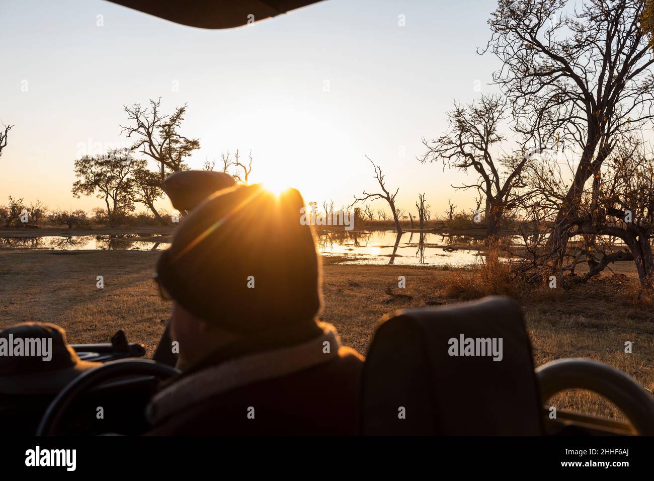 Un chauffeur en jeep qui regarde le lever du soleil. Banque D'Images