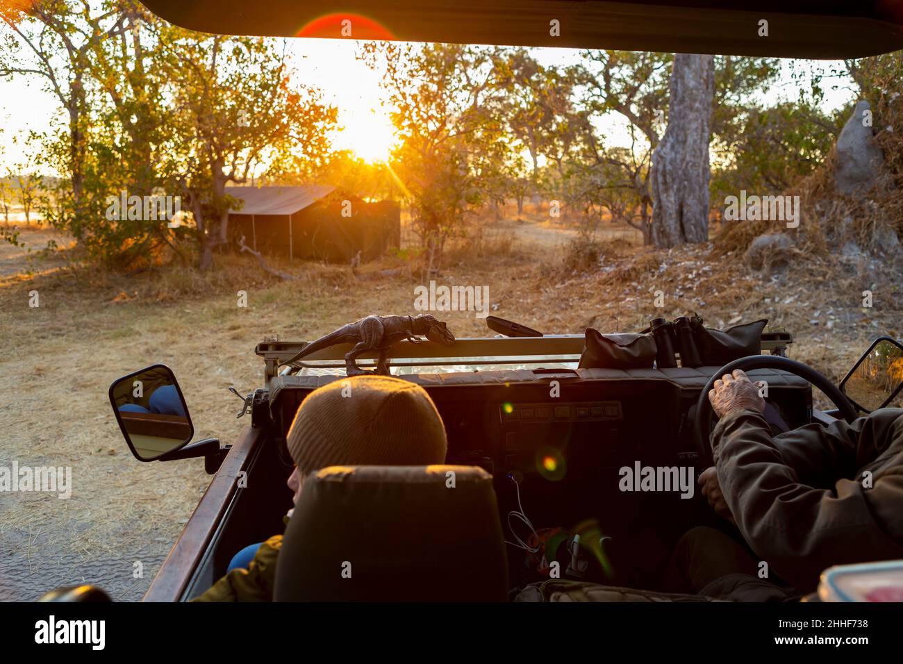 Une jeep safari, vue sur la route de terre devant au lever du soleil, éclat de lentille Banque D'Images