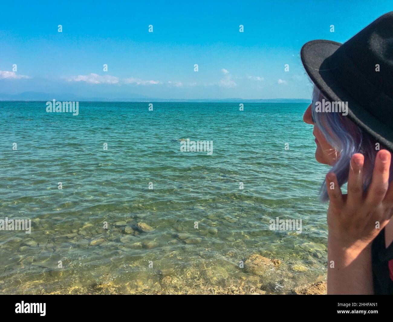 Une femme portant un chapeau regardant la mer horinzont Banque D'Images