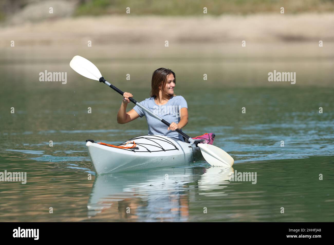 Femme en kayak regardant à côté dans un lac tranquille pendant les vacances d'été Banque D'Images