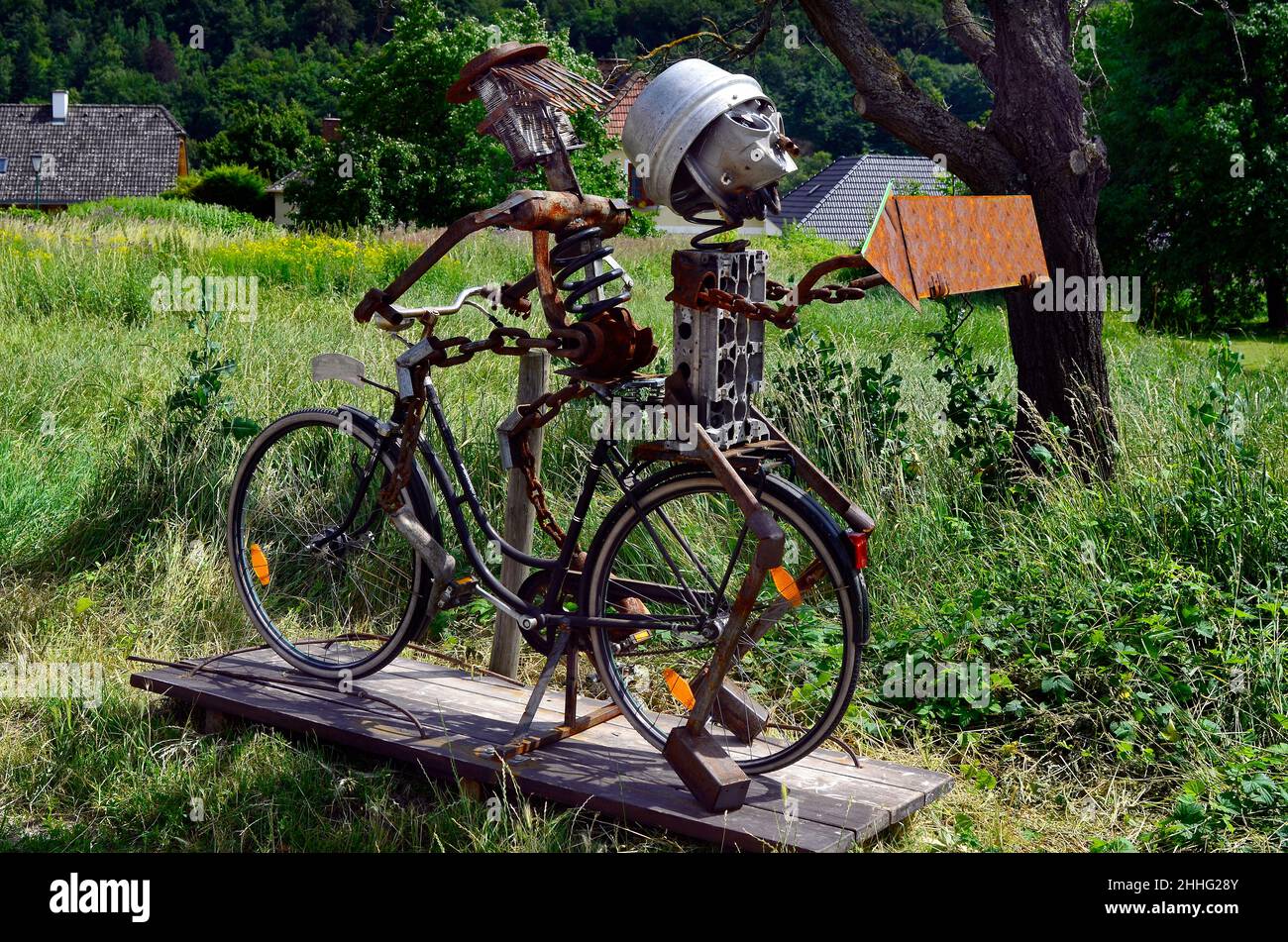 Autriche, caractère drôle construit à partir de pièces de rechange assis sur un vélo avec un panneau de direction dans le site du patrimoine mondial de l'UNESCO dans la vallée du Danube Banque D'Images