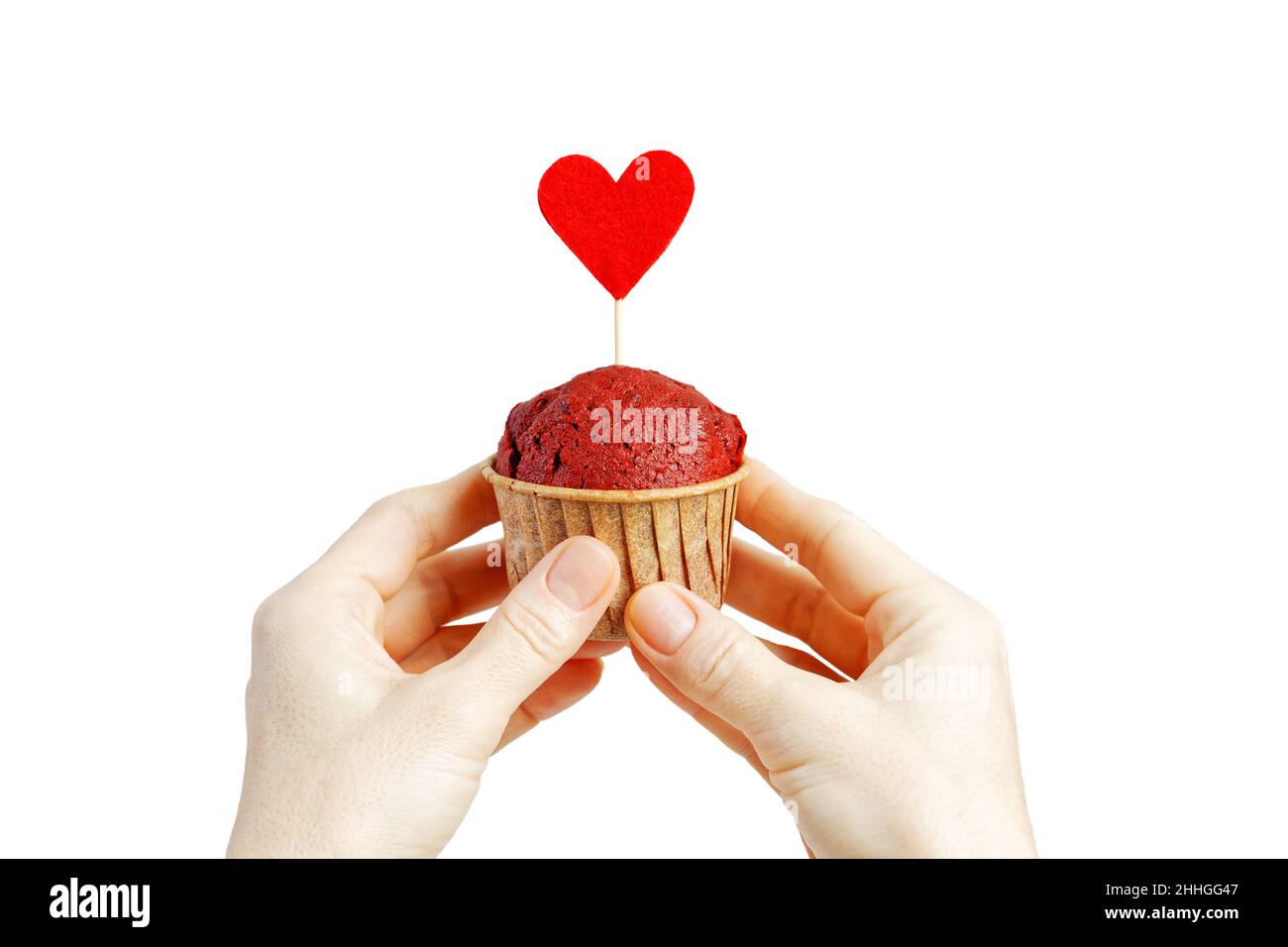 Gros plan mains tenant un cupcake en velours rouge décoré avec coeur en feutre rouge isolé sur fond blanc. Banque D'Images Gros plan mains tenant un cupcake en velours rouge décoré avec coeur en feutre rouge isolé sur fond blanc. Banque D'Images