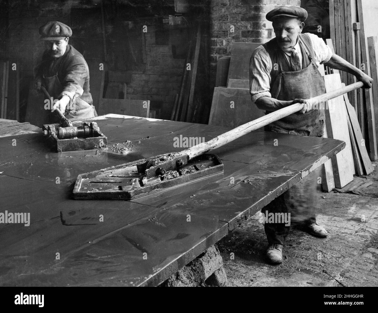 Lit de billard flottant à Dinorwic Slate Wharf, Rotherhithe.La division de l'ardoise est un art acquis par une longue pratique.Il s'agit d'une occupation inhabituelle du côté de la Tamise, bien que les carrières galloises emploient de nombreux hommes qualifiés.Cinq dalles d'ardoise sont réunies pour former un lit.Ils sont complètement frottés à plat avec des flotteurs - des boîtes métalliques remplies de sable et d'eau.11th février 1928. Banque D'Images