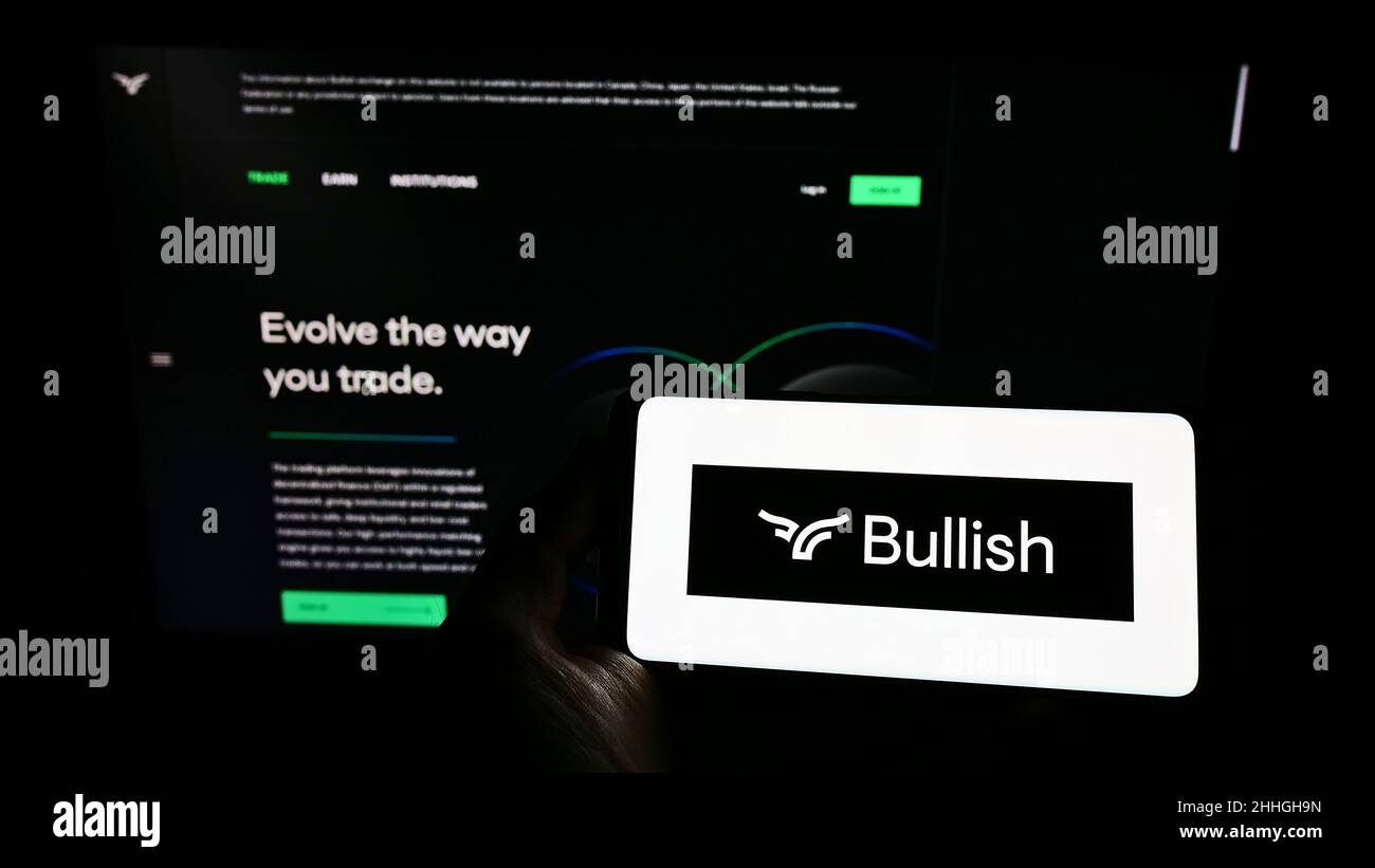 Personne tenant un smartphone avec le logo de la société d'échange de crypto-monnaies bullish Global à l'écran devant le site Web.Mise au point sur l'affichage du téléphone. Banque D'Images